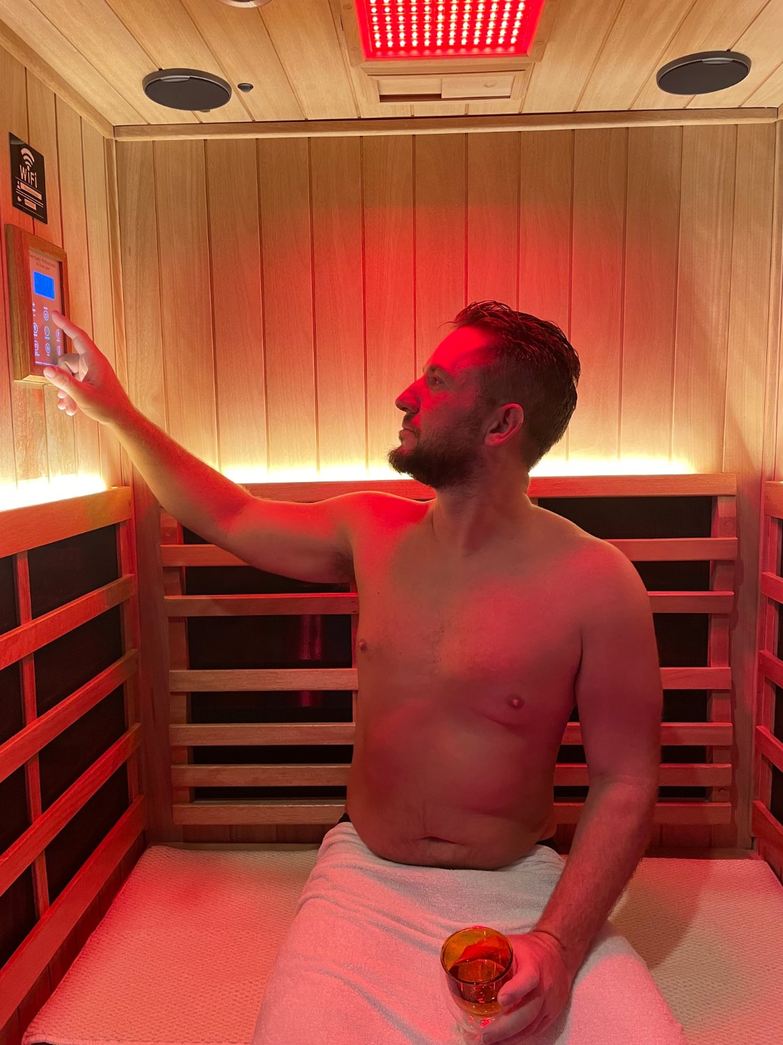 Guest adjusting the sauna controls beneath the red light panel